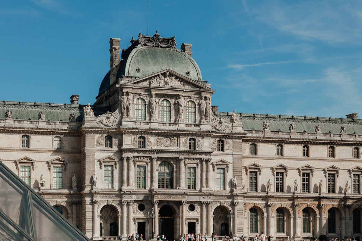 Exterior view of the Louvre Museum under a clear blue sky