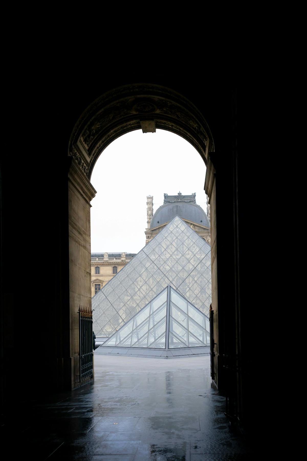 The Louvre Pyramid framed by a stone archway