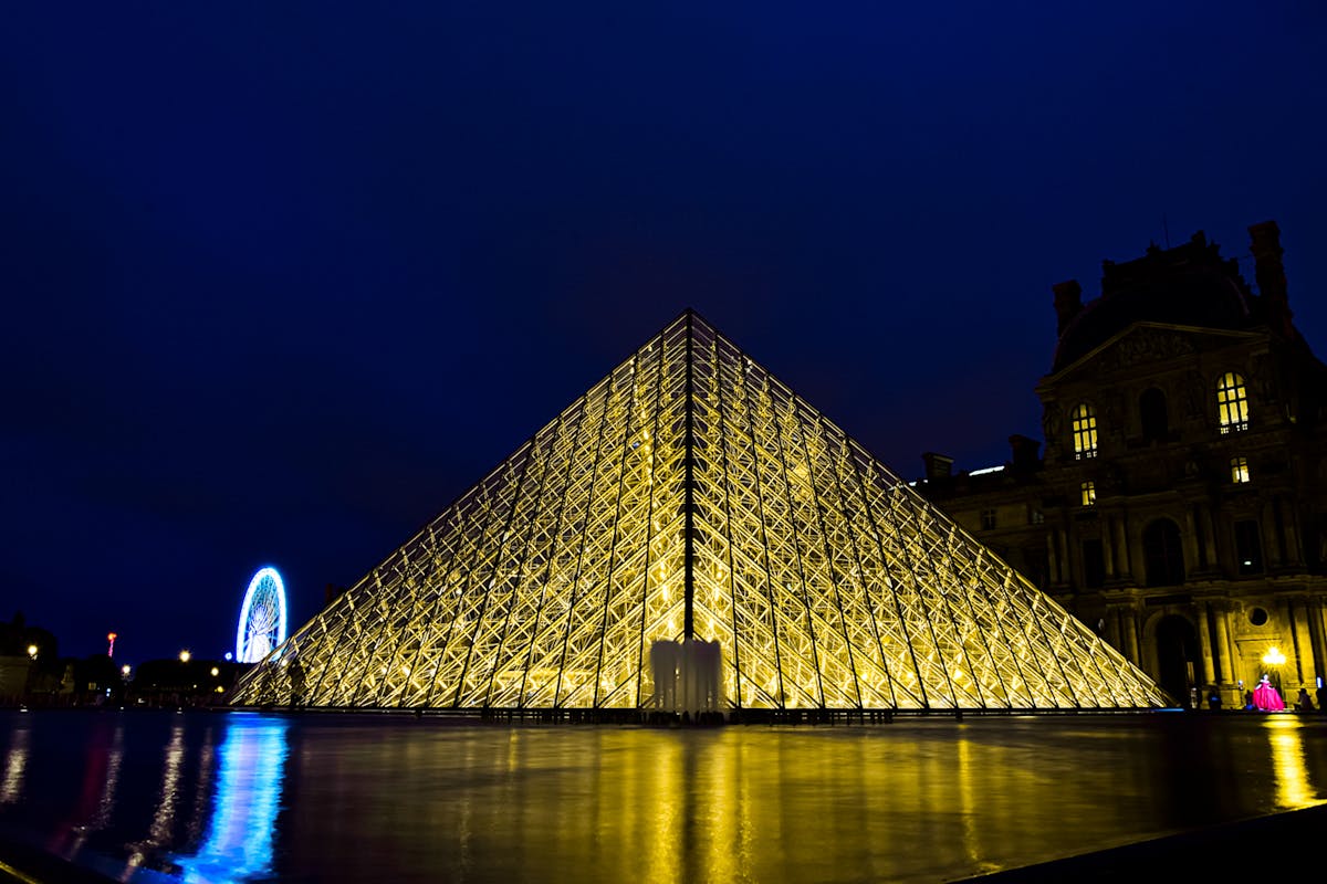 The Louvre Pyramid illuminated with golden light at night