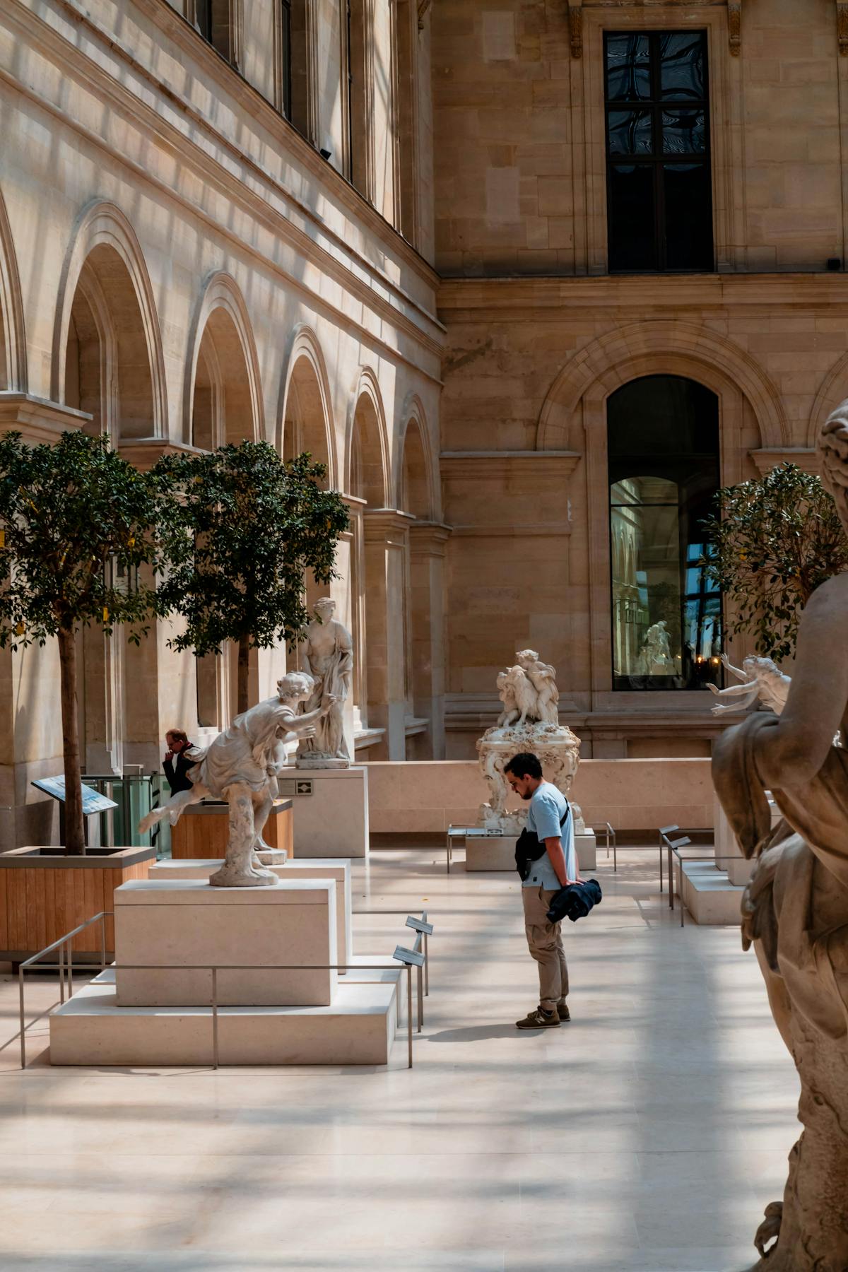 Visitor admiring sculptures in a Louvre gallery