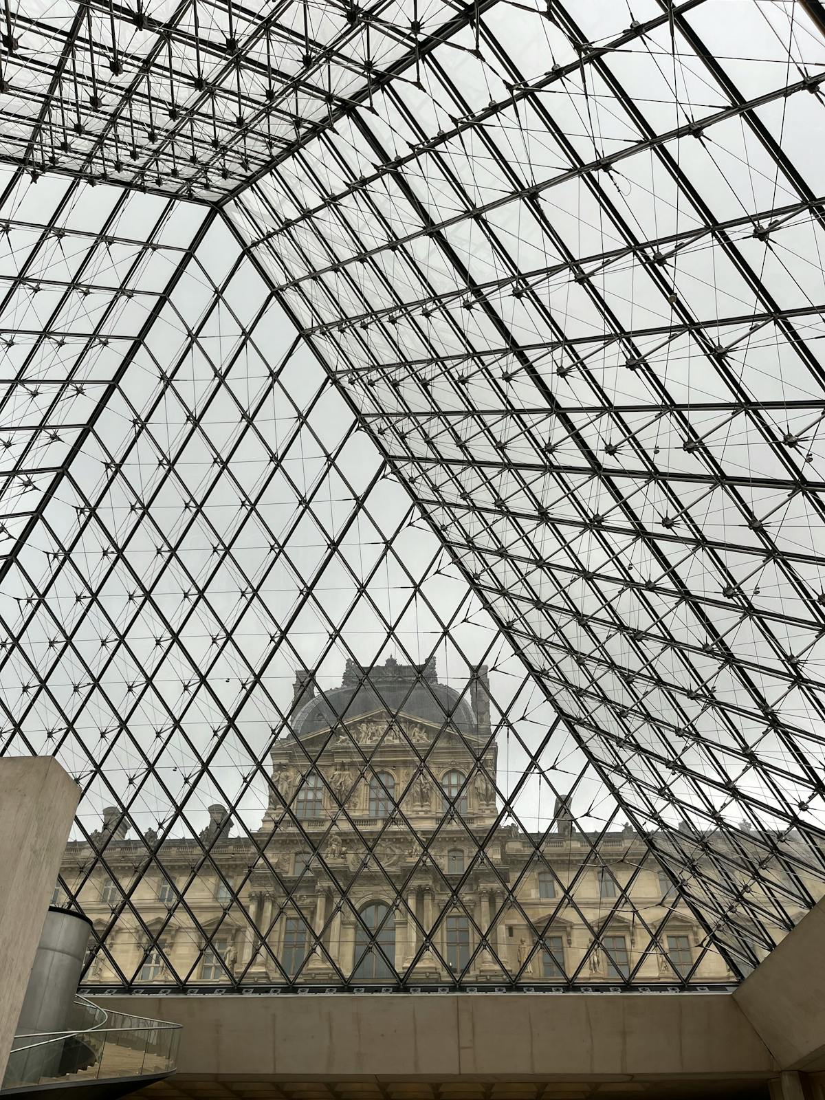 View of the Louvre Museum building through the glass panels of the famous pyramid