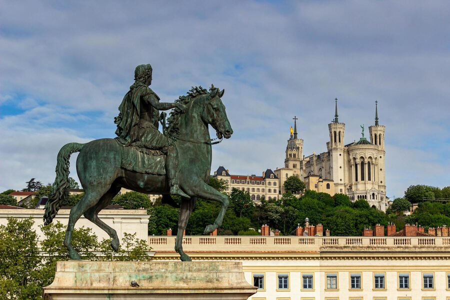 Equestrian statue of Louis XIV with Basilica of Notre-Dame de Fourviere in background at Place Bellecour Lyon