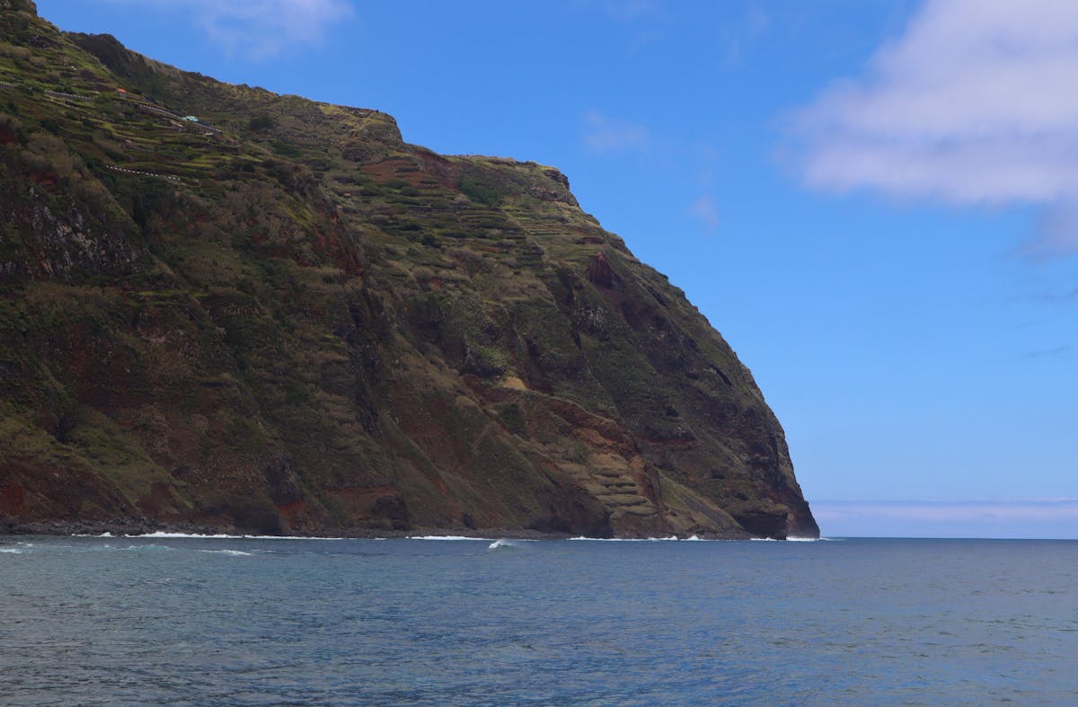 Dramatic cliff coastline of Madeira island against blue sky and Atlantic ocean