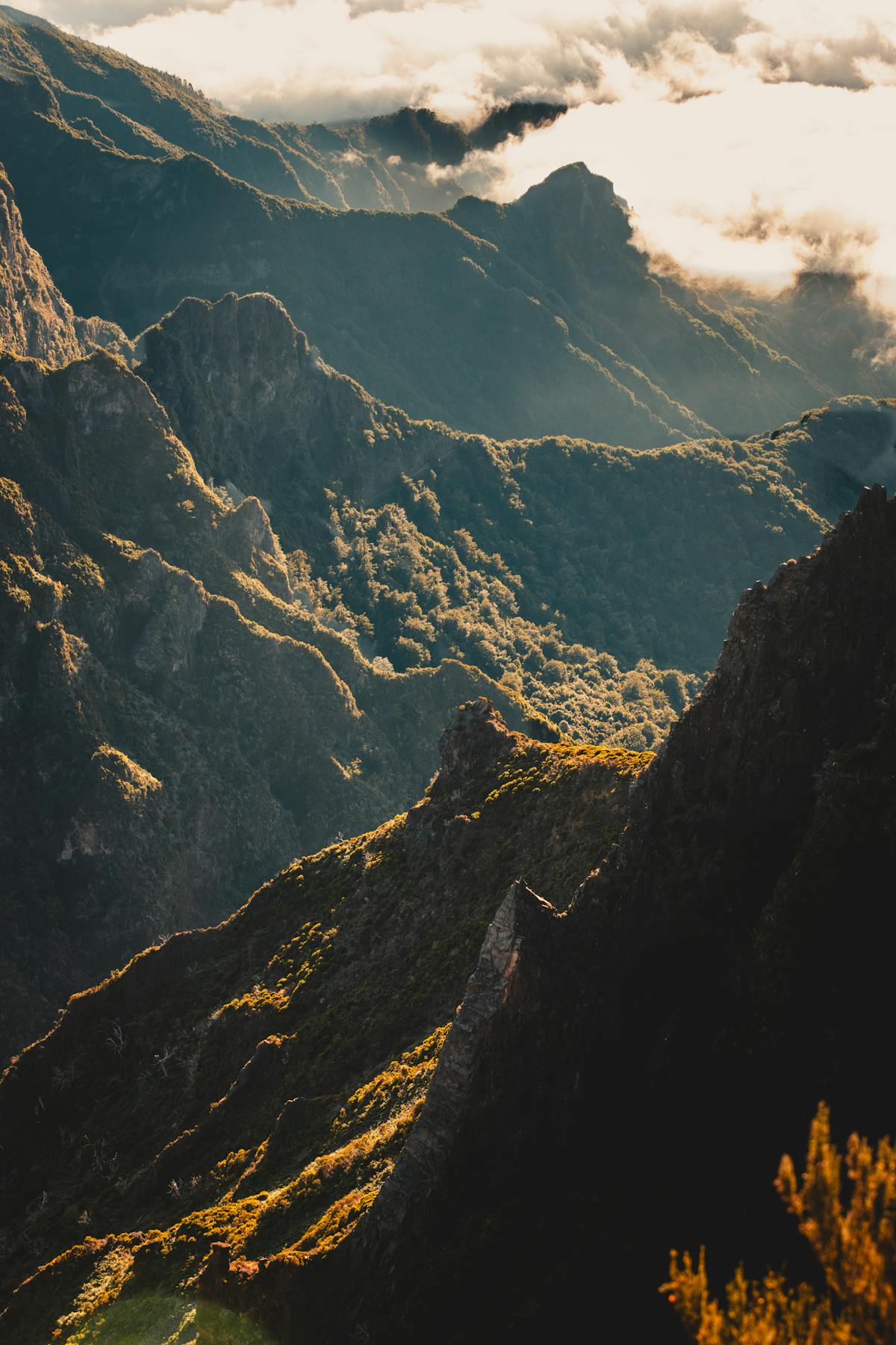 Warm sunrise light illuminating the mountain peaks of Madeira with clouds below