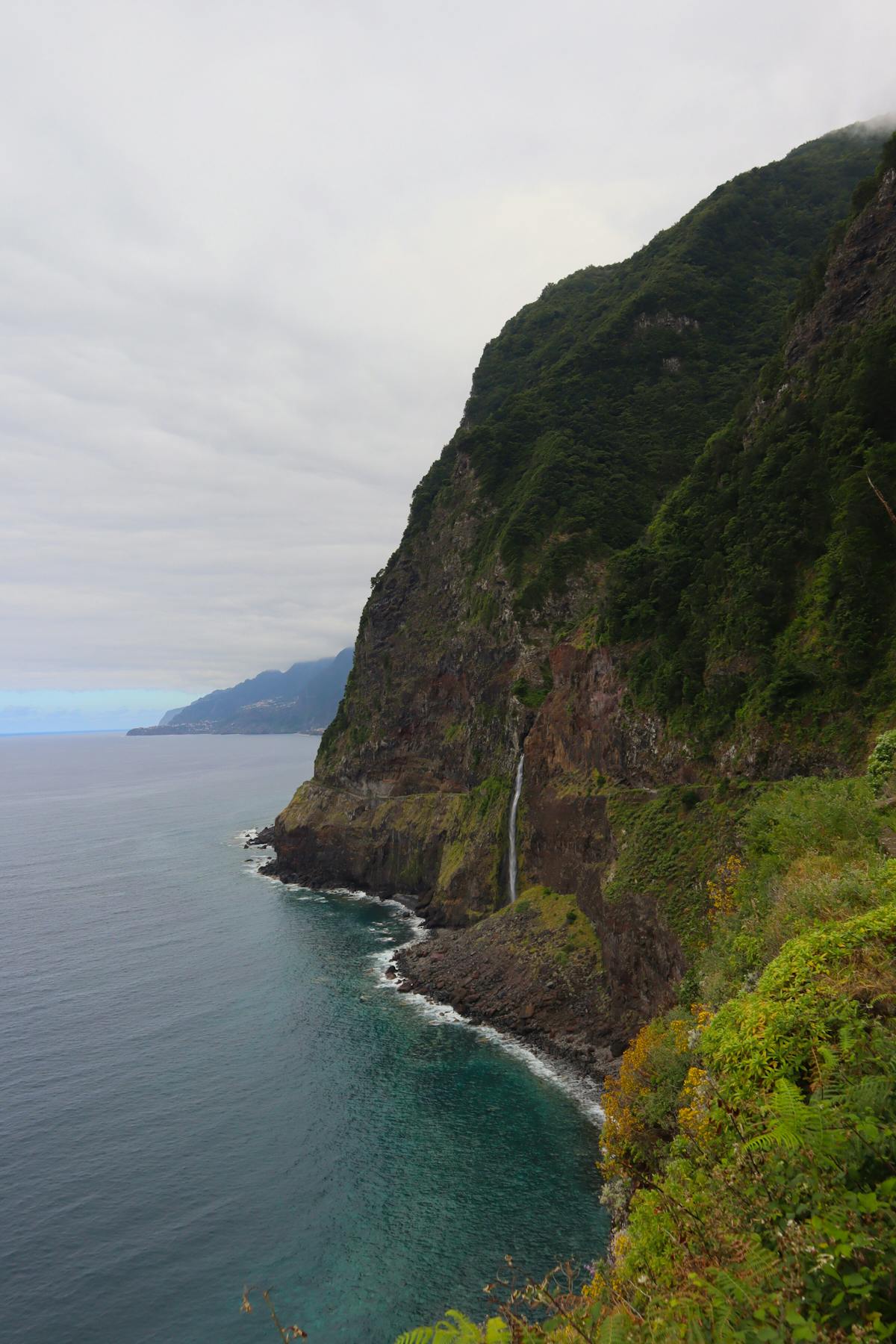 Waterfall cascading down cliffs into the Atlantic Ocean in Madeira