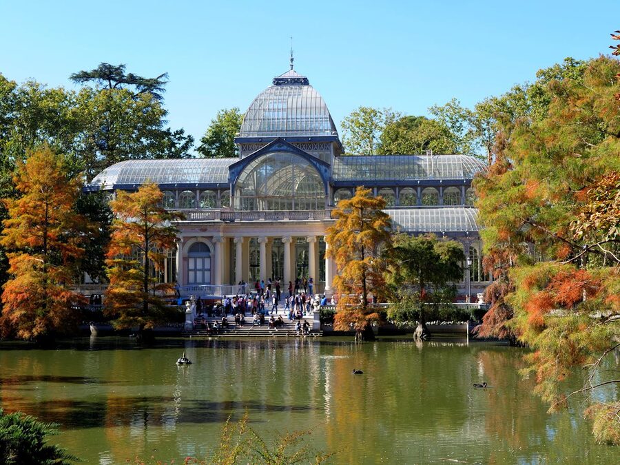 Palacio de Cristal surrounded by autumn trees in Retiro Park Madrid