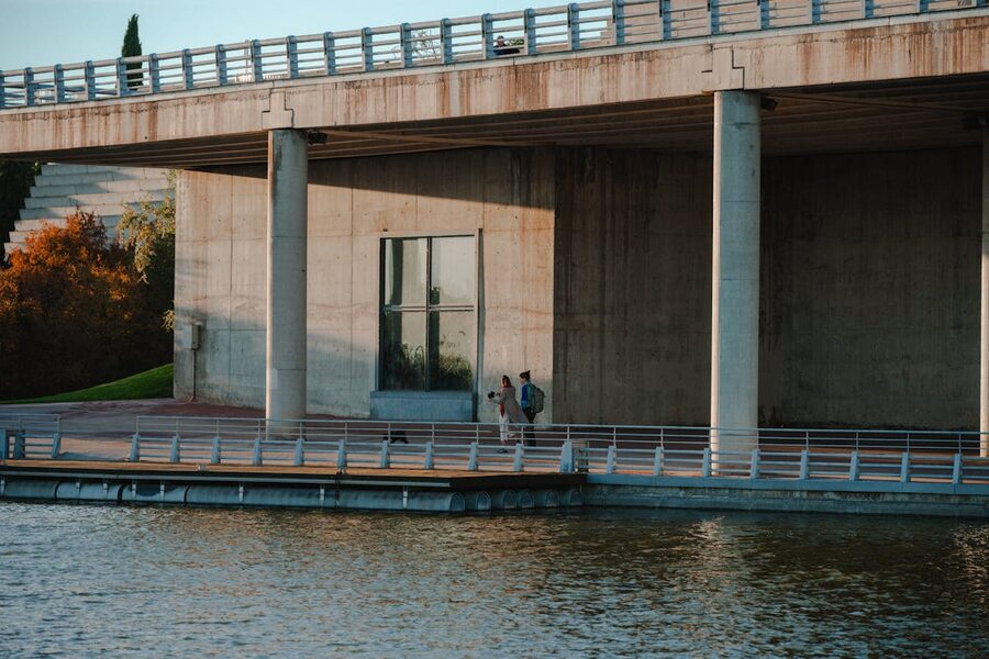 Couple walking beneath a concrete bridge by the water along the Manzanares River in Madrid