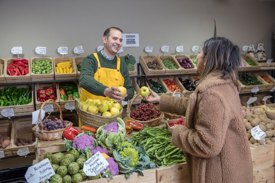 Market vendor exchanging fresh fruits with customer in Madrid