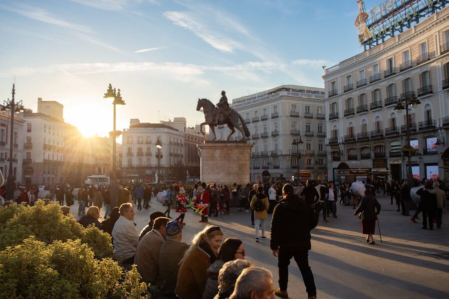 Puerta del Sol in Madrid at sunset with travelers gathered around the King Charles III statue