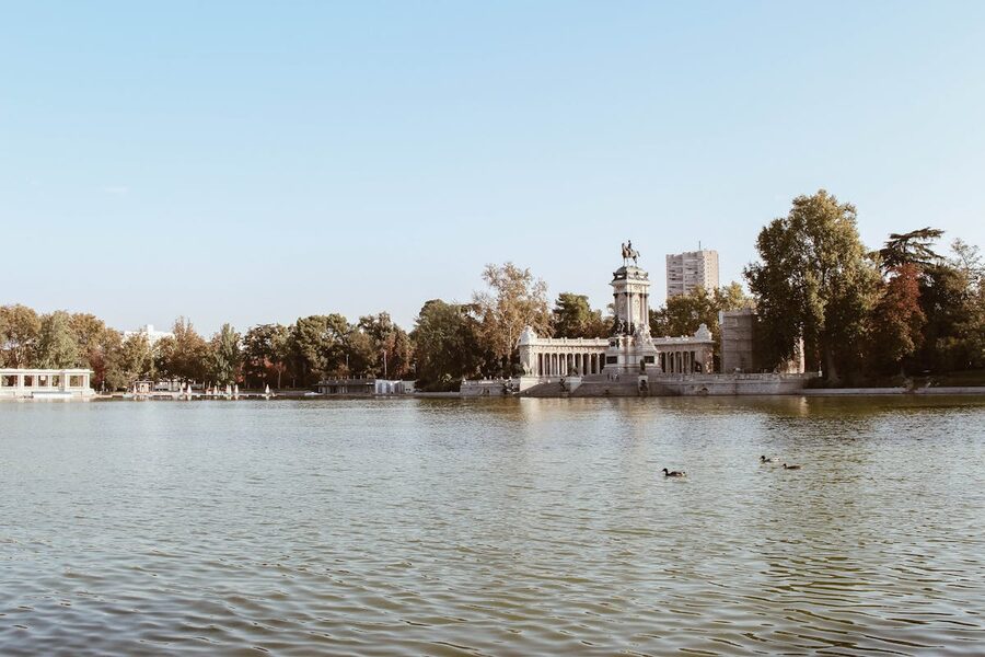 Monument and lake at El Retiro Park in Madrid under a clear blue sky