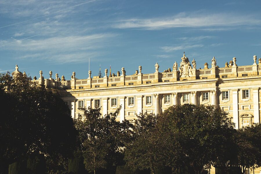 Royal Palace of Madrid surrounded by lush green gardens on a sunny day