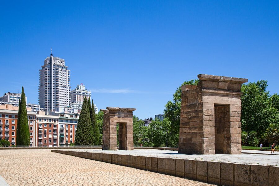 Ancient Temple of Debod in Madrid with modern cityscape behind it