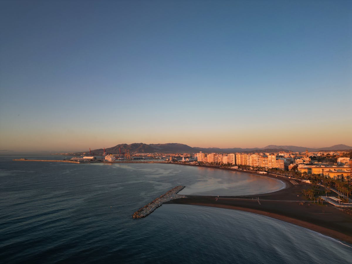 Aerial view of Malaga coastline with sunlit buildings at sunset