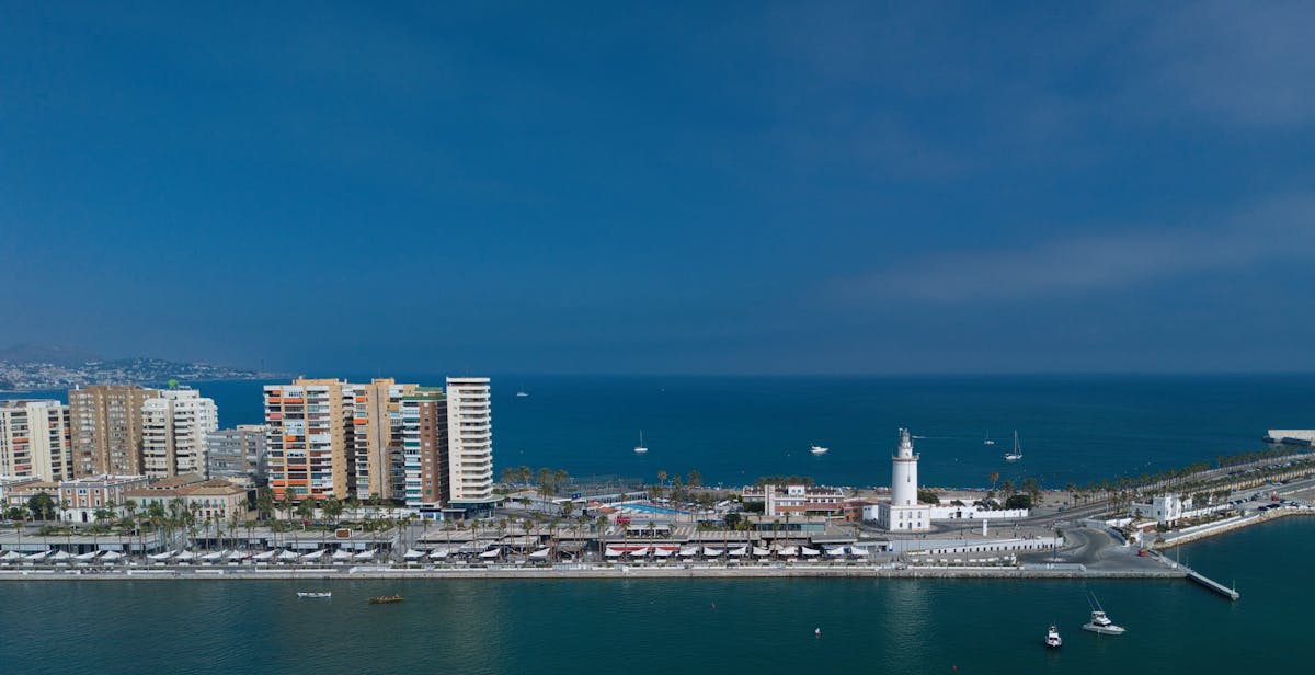 Aerial view of Malaga harbour showing the waterfront skyline and lighthouse under a clear blue sky
