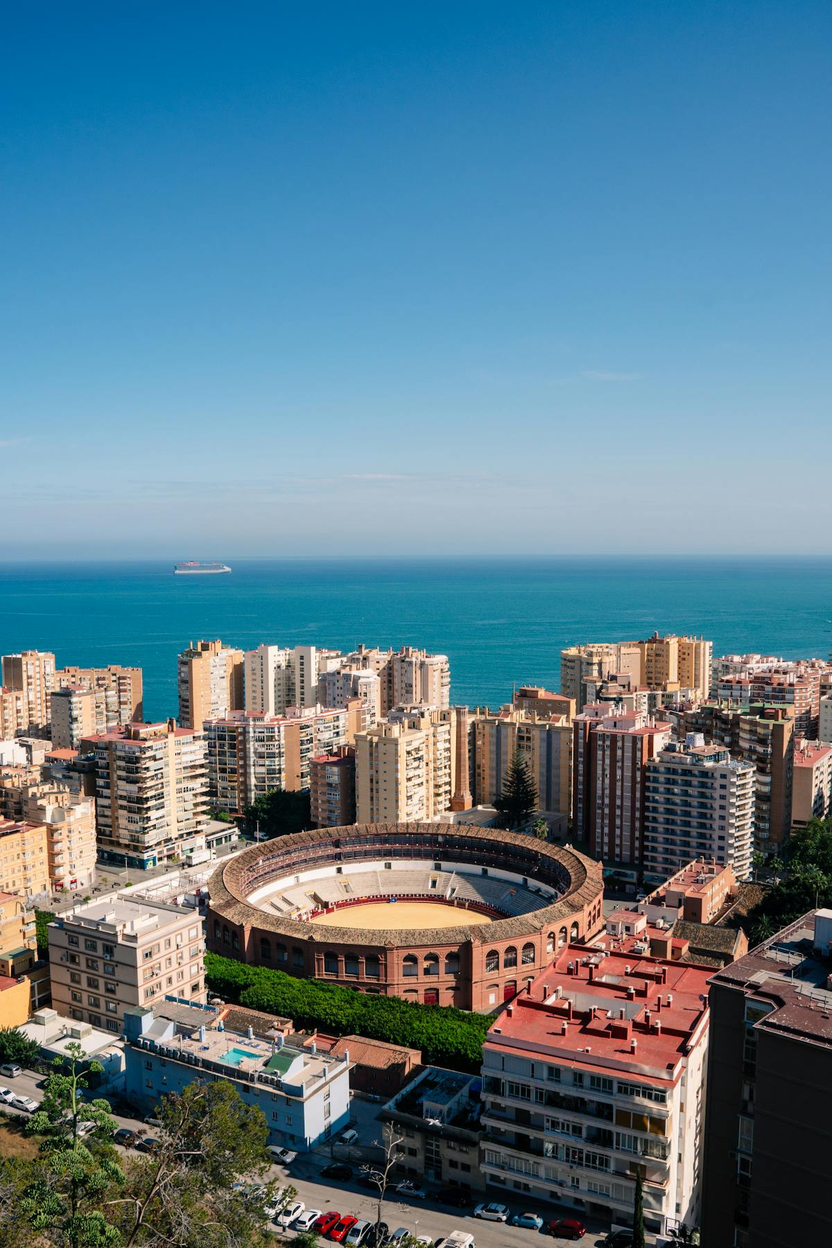 Stunning aerial view of the Malaga bullring and Mediterranean coastline from above the city