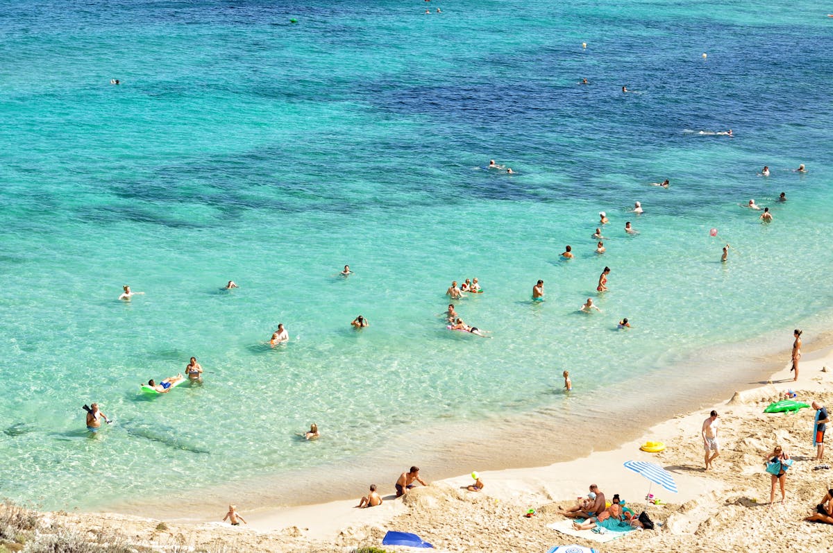 People enjoying a sunny beach day in Mallorca Spain with turquoise water and sandy shores