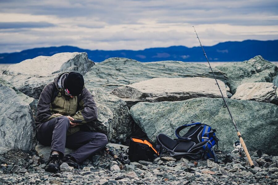 Man fishing from rocky shore in a Norwegian fjord