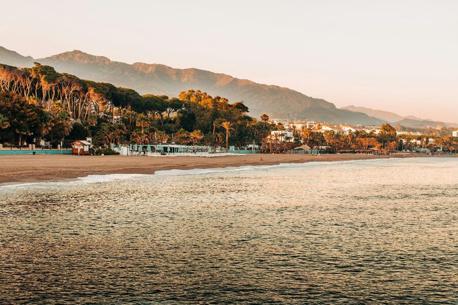 Peaceful sunrise over Marbella beach with mountains and lush greenery