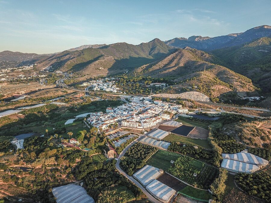 The small white village of Maro perched on a hillside near Nerja with mountain ridges behind
