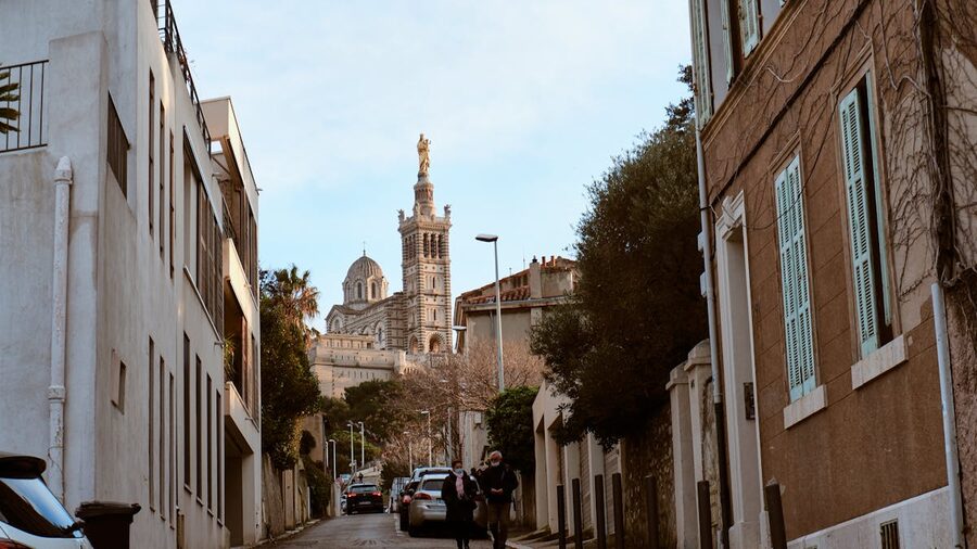 Historic Marseille street scene with Notre-Dame de la Garde basilica visible above the rooftops