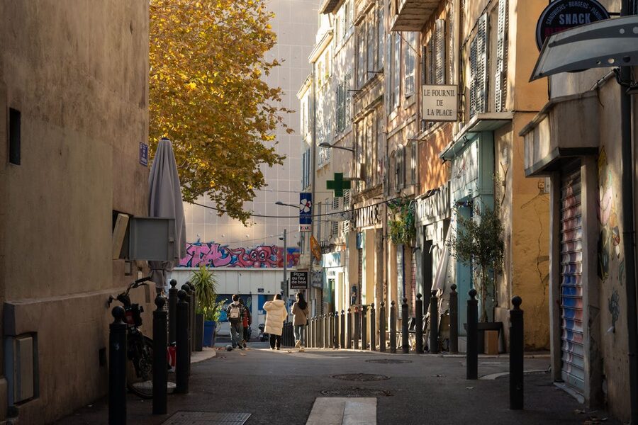 People walking through a warm sunlit Marseille street at golden hour