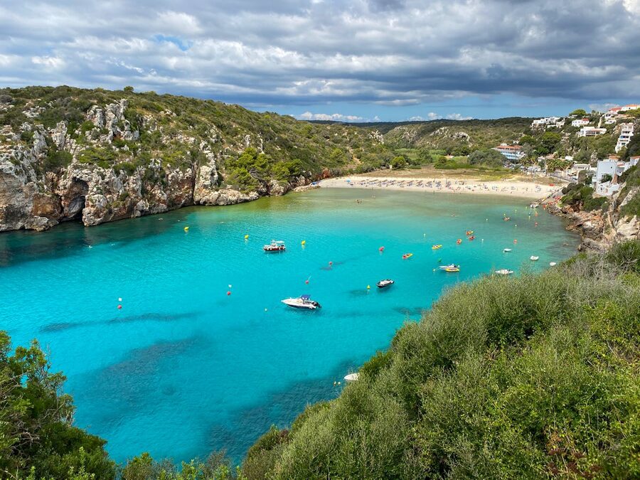 Aerial view of Cala en Porter beach with turquoise waters and cliff-lined cove in Menorca
