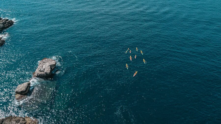 Aerial view of kayakers paddling through blue coastal waters