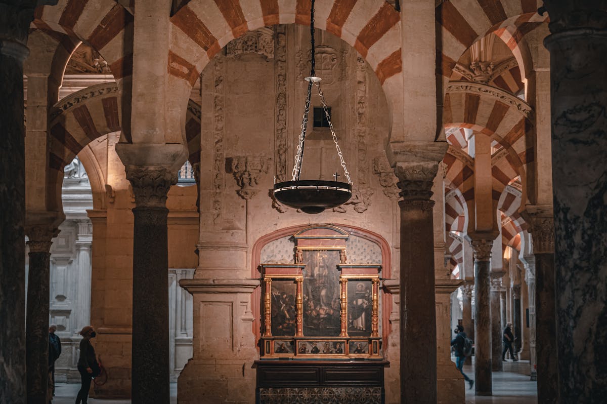 Ornate historical artwork and striped arches in a side chapel of the Mosque-Cathedral