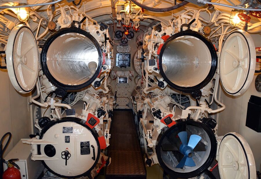 Interior view of a submarine torpedo room showing the mechanical systems