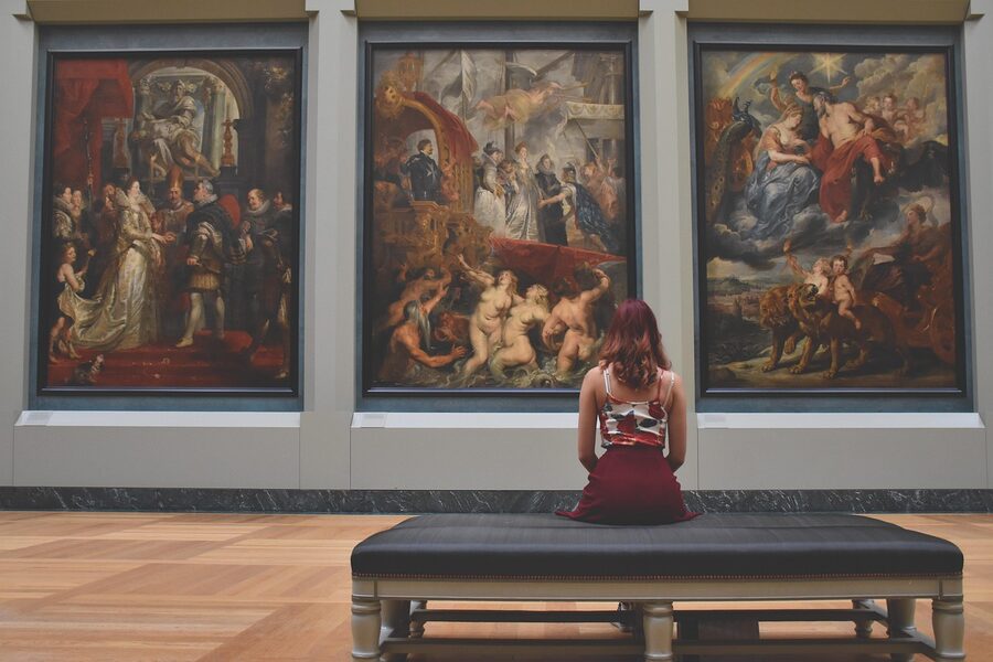 Visitor standing in an art gallery viewing paintings on the wall