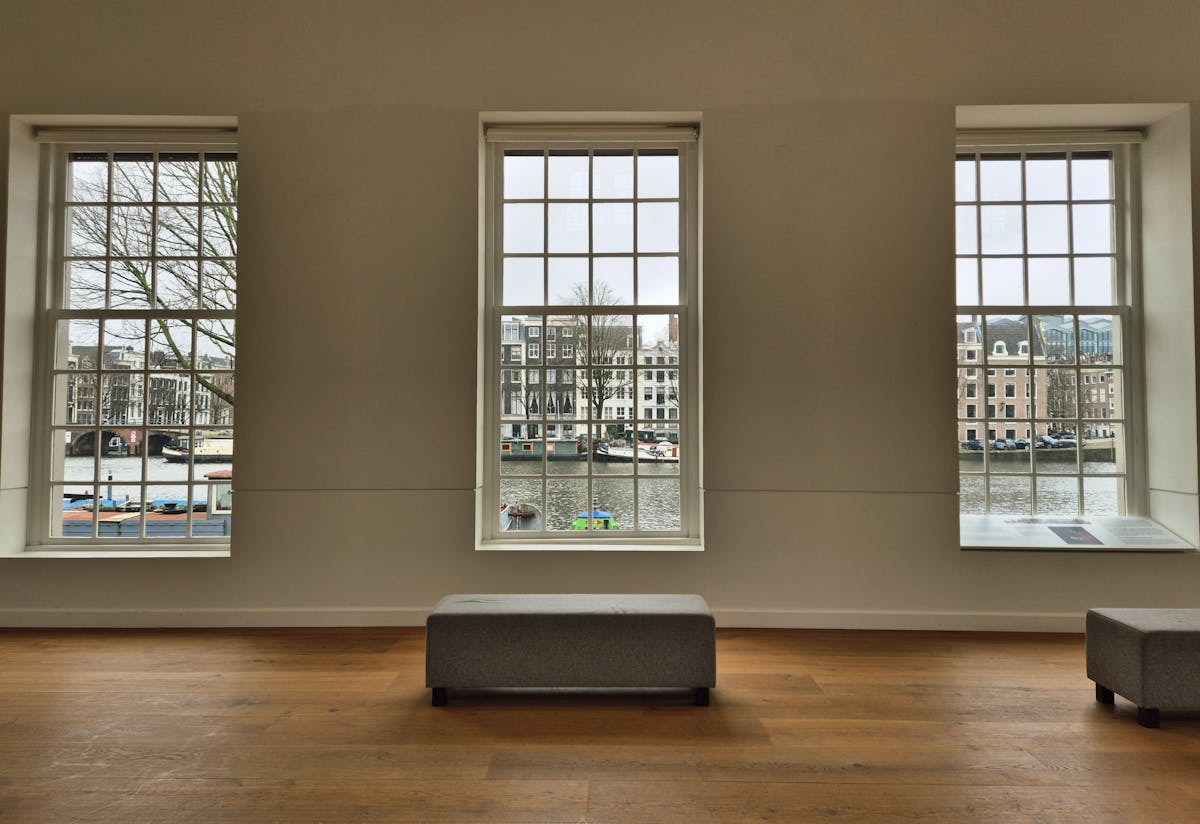 Bright gallery interior with large windows overlooking an Amsterdam canal