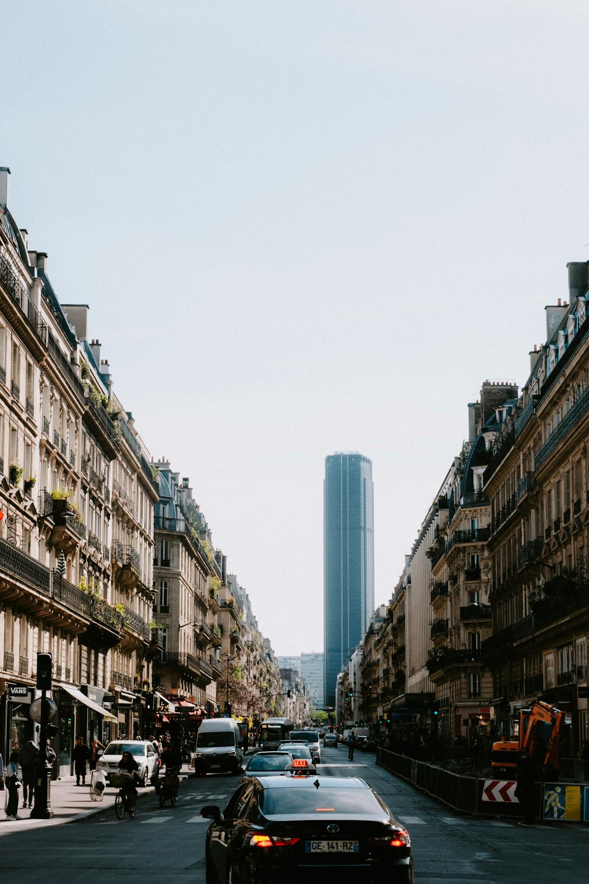 Paris city street with the Montparnasse Tower visible in the background among classic Haussmann buildings