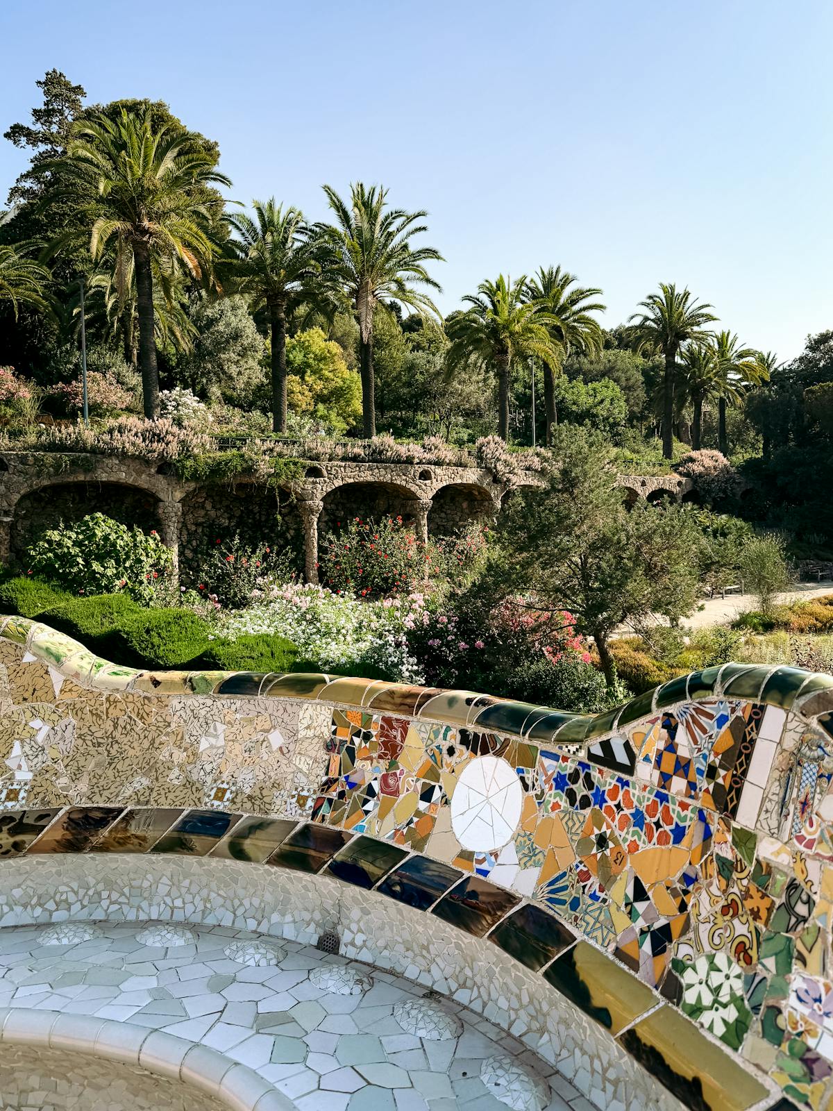 Vibrant mosaic bench and palm trees at the main terrace of Park Guell