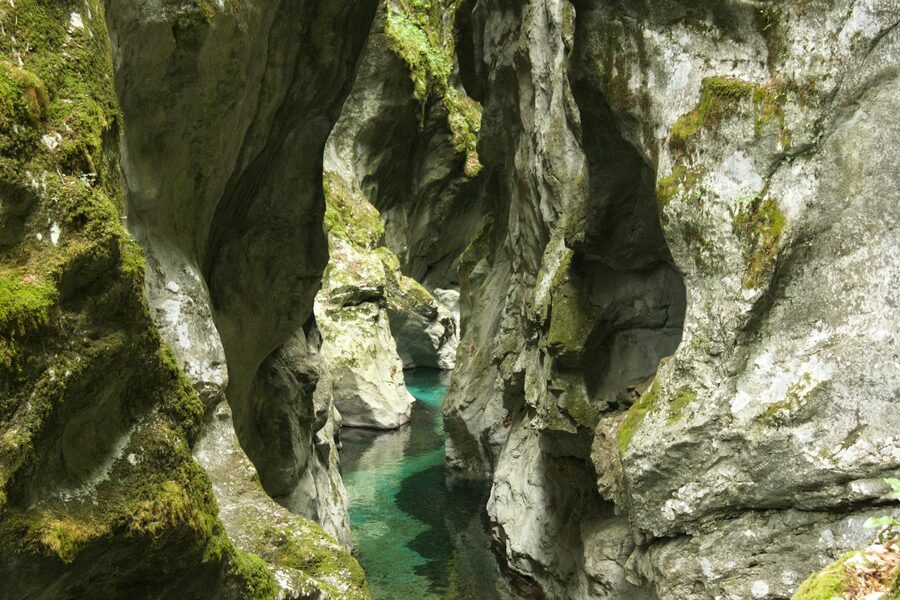 Moss-covered canyon cliffs with crystal-clear river flowing below