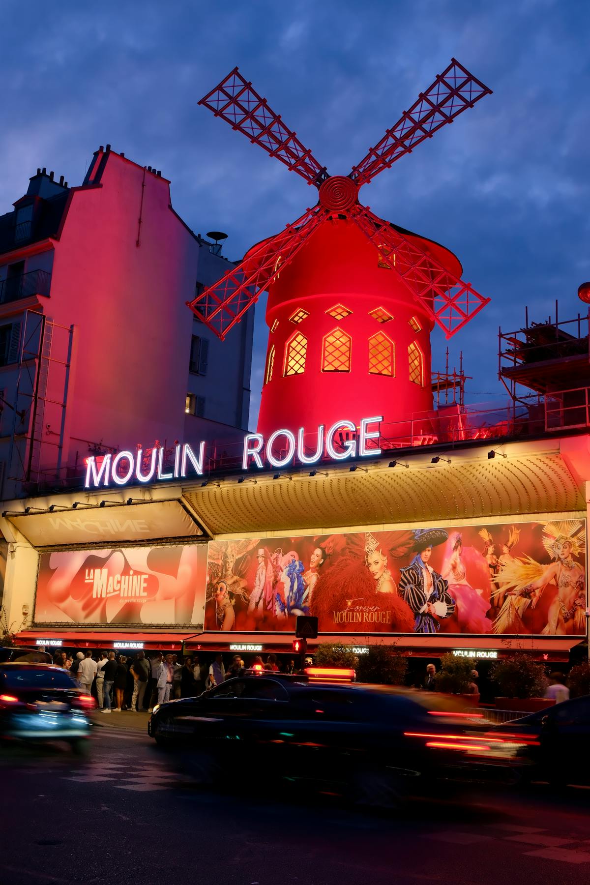 The Moulin Rouge glowing warmly against the Paris night sky in Montmartre