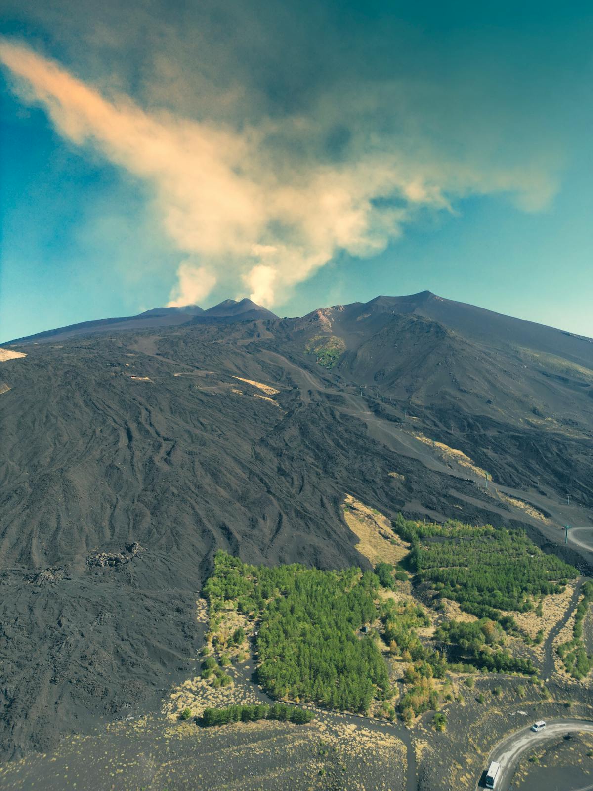 Black lava fields stretching across Mount Etna slopes from above