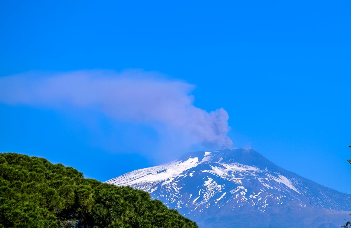 Mount Etna covered in snow under a bright blue sky