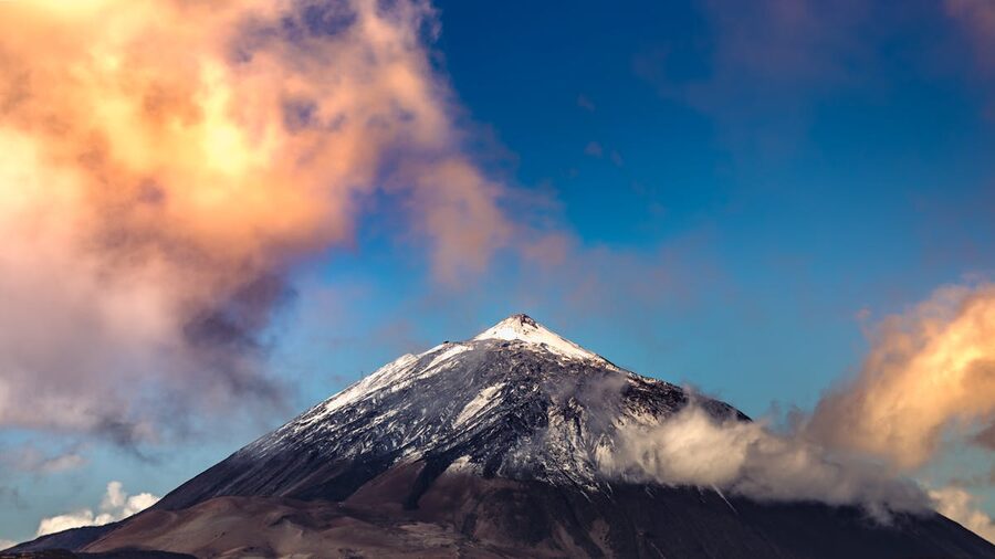 Mount Teide peak surrounded by colorful sunset clouds