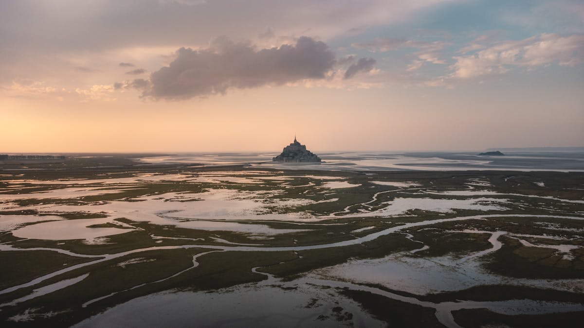 Aerial view of Mont Saint-Michel at sunset with reflective tidal flats