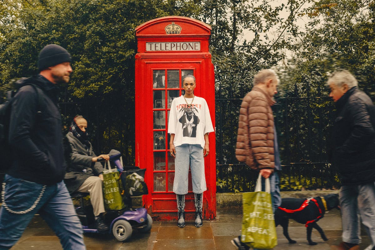 London sidewalk with classic red phone booth and people walking past
