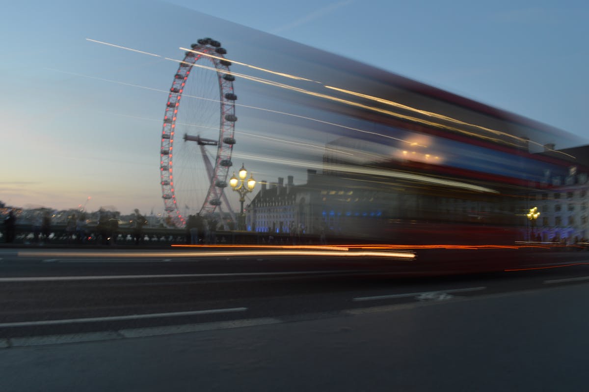 Red London bus passing the London Eye at twilight