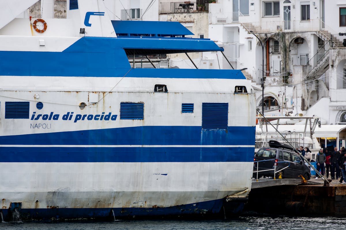 A ferry docked at the port in Naples Italy with Mediterranean architecture in the background