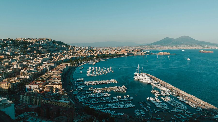 Naples harbor with boats and waterfront buildings under clear sky