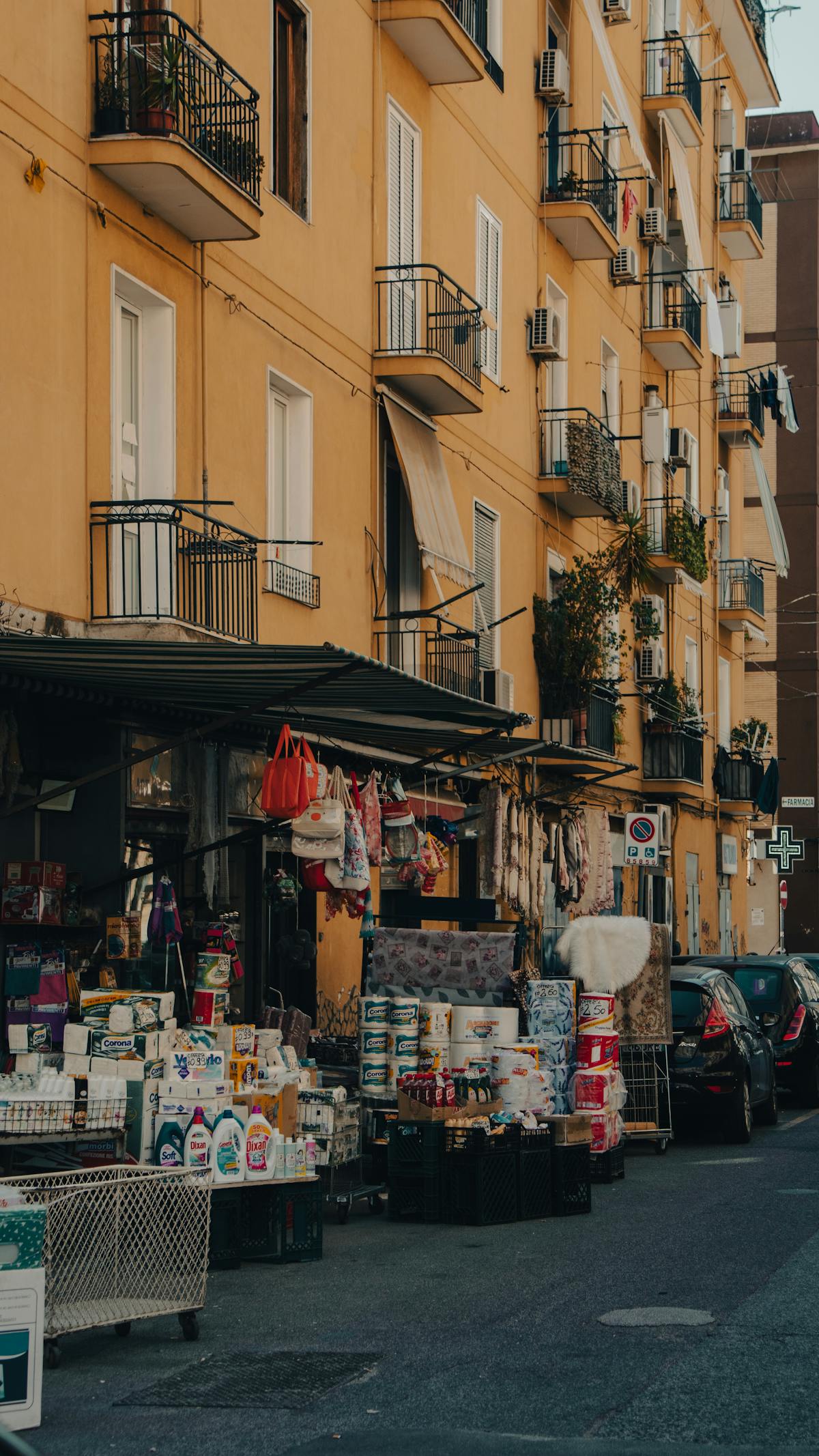 Street market in Naples with goods on display and yellow building facade