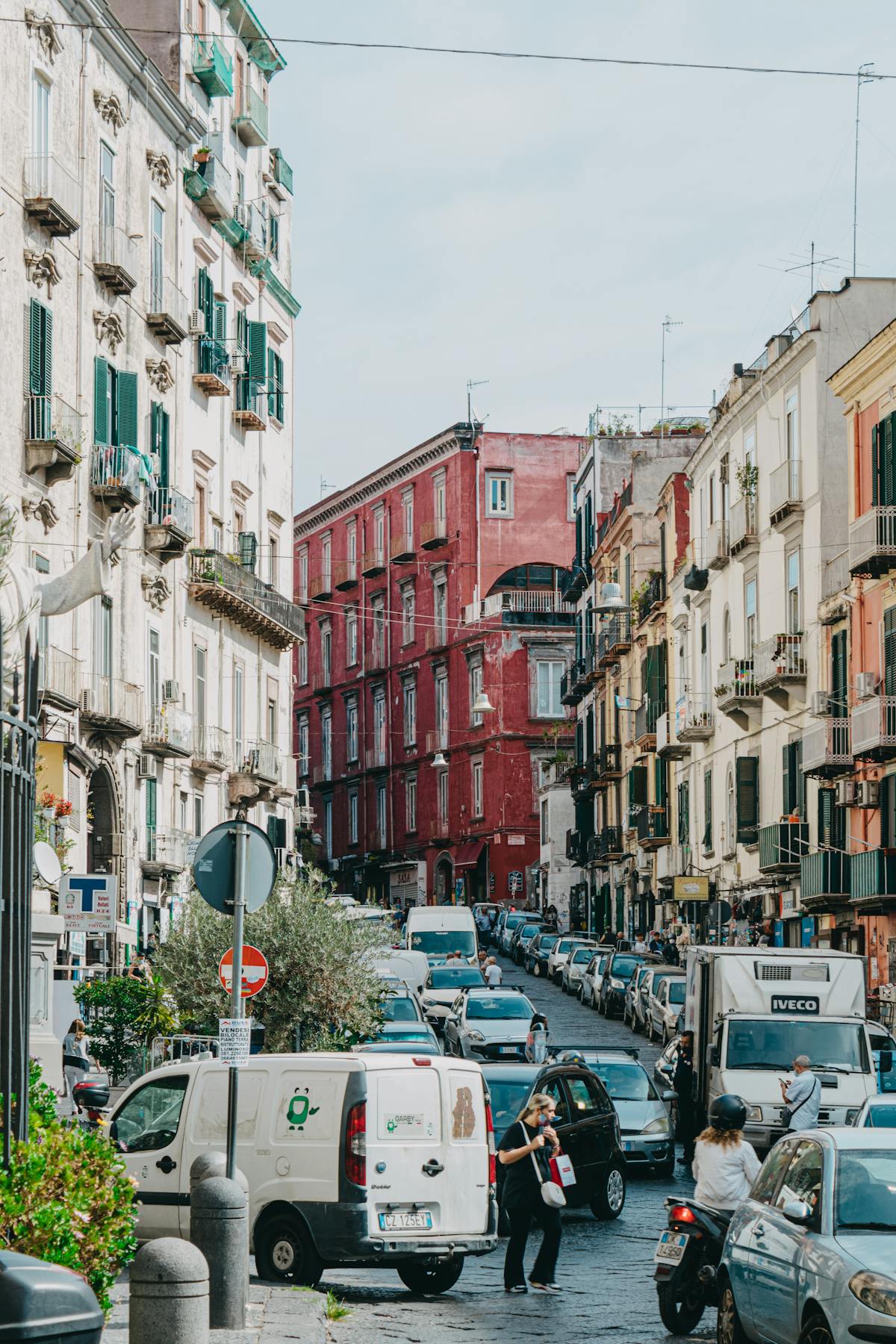 A lively street scene in Naples with historic buildings and parked scooters