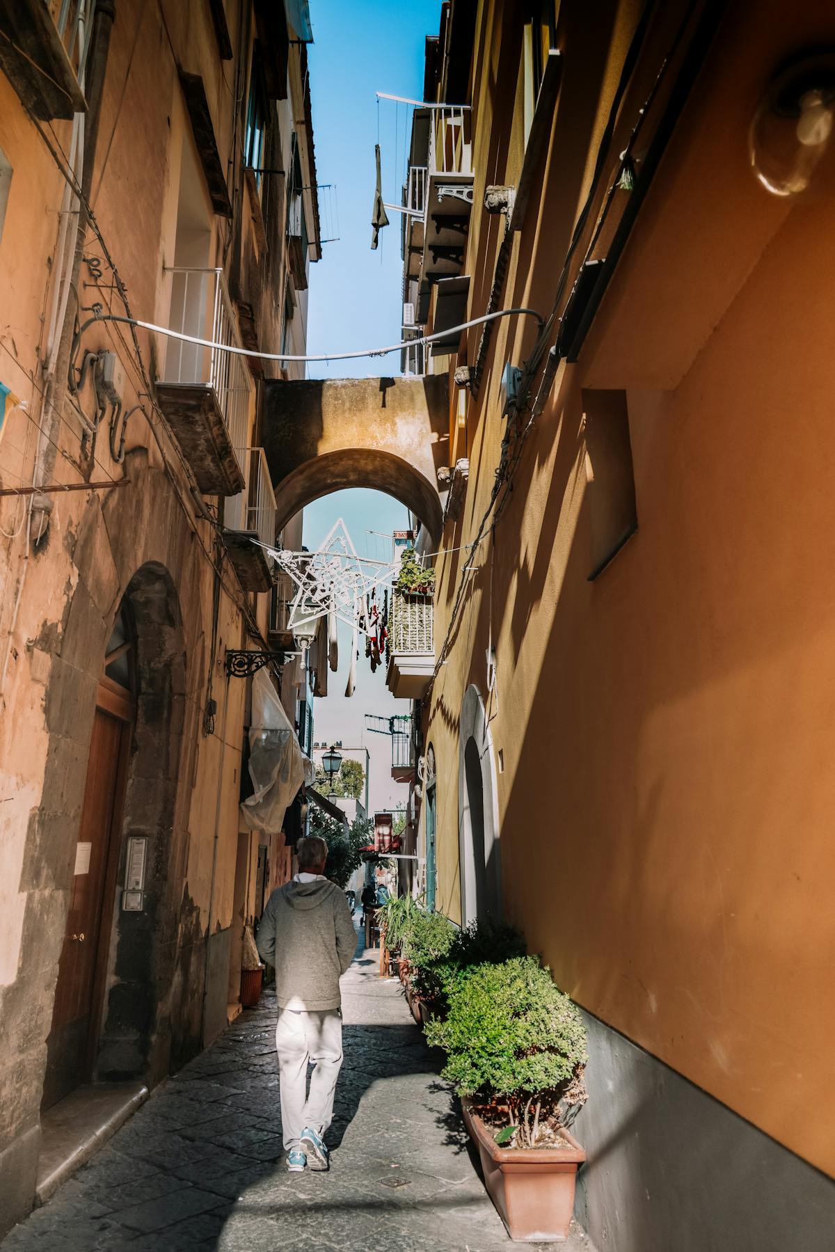 A person walking through a sunlit narrow alley in a historic city