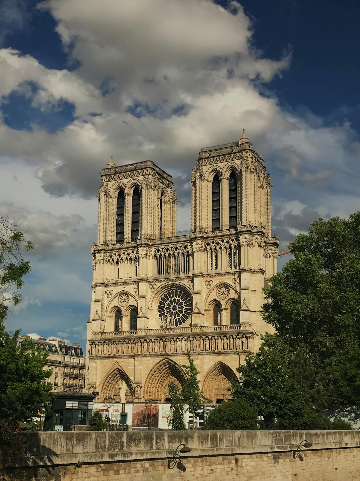 Full view of Notre-Dame Cathedral in Paris displaying the complete Gothic facade with spire and buttresses