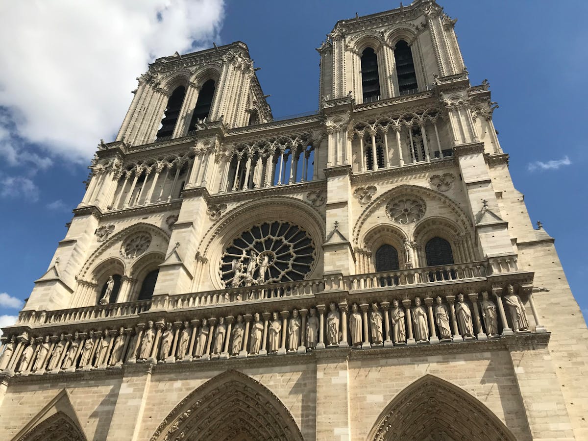 Low angle view of Notre-Dame Cathedral towers rising above the roofline against blue sky