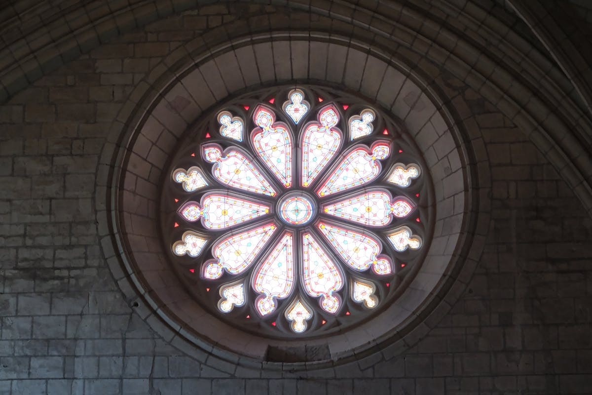 Detailed view of a circular stained glass rose window with intricate medieval patterns in a cathedral