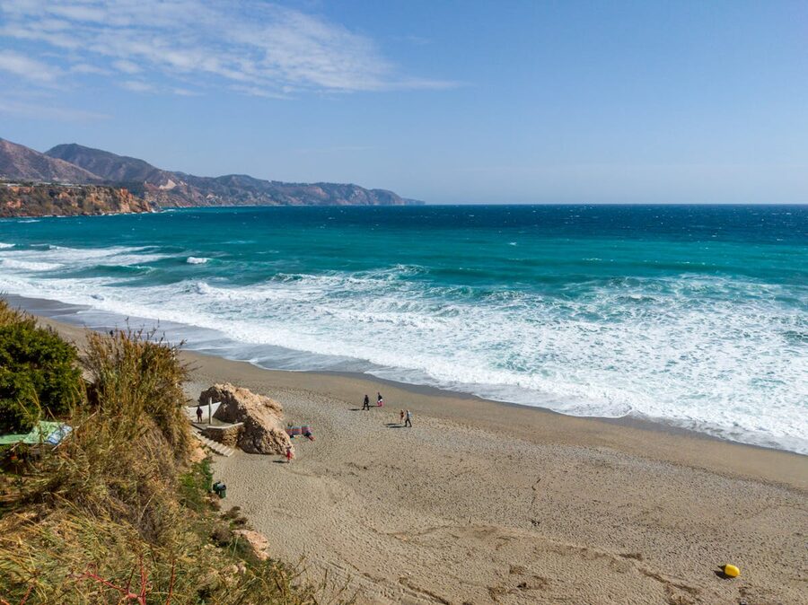 Aerial shot of Nerja coastline showing turquoise Mediterranean waters and sandy beach